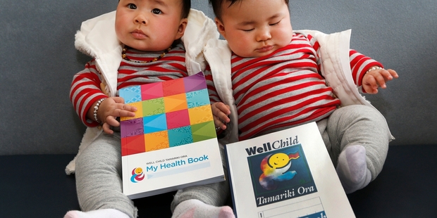 Ella Gao (left) shows off the new health book which replaces the one her twin sister, Grace, has. Photo / Mark Mitchell