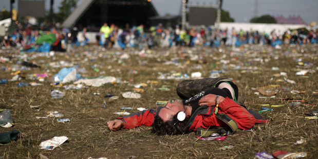 A festival goer rests among litter strewn across the field near to the main Pyramid Stage of the Glastonbury Festival. Photo/AP