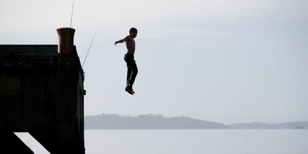 Last month is shaping up as one of the warmest Junes on record. Tamehama Martin jumps off the wharf at Magazine Bay near Maraetai. Photo / Richard Robinson