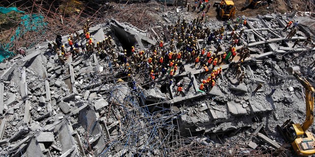Rescuers, search for workers believed buried in the rubble of a building that collapsed late Saturday during monsoon rains on the outskirts of Chennai, India. Photo / AP