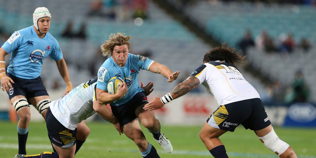 The Waratahs' Michael Hooper, centre, is tackled during the Super Rugby match between the Waratahs and the Brumbies in Sydney on Saturday night. Photo / AP