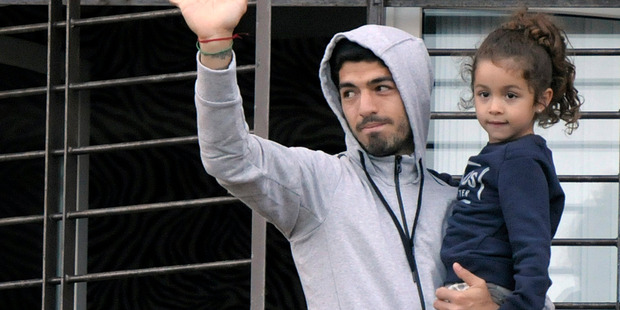 Uruguay's soccer player Luis Suarez holds his daughter as he greets fans from their home's balcony on the outskirts of Montevideo, Uruguay. Photo / AP