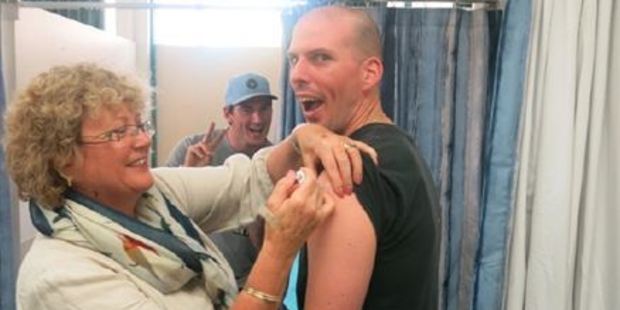 Howick resident and nurse Gillian Davies vaccinates her son-in-law Michael Briscoe of Howick, while his brother Stephen Briscoe of Half Moon Bay looks on. Photo / supplied