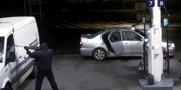 The masked man, who arrived in the silver Nissan in the background, points a gun at the Armourguard van window and demands money.