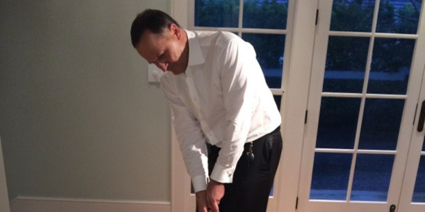 John Key tries out his presidential putter which carries the United States presidential seal and Barack Obama's signature.