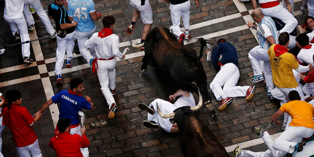 Dolores Aguirre's ranch fighting bulls jump over fallen revelers during the running of the bulls of the San Fermin festival, in Pamplona, Spain. Photo / AP
