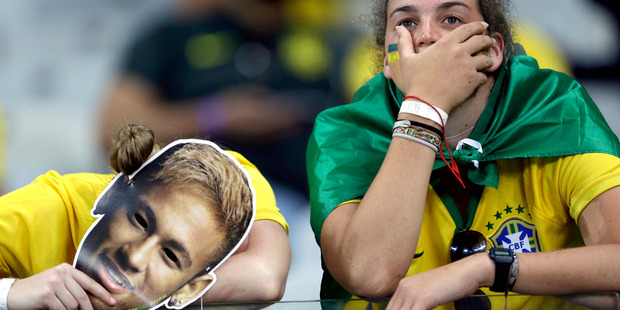 Brazil supporters holding Neymar face masks react after Germany defeated Brazil 7-1 to advance to the finals during the World Cup semifinal soccer match between Brazil and Germany. Photo / AP