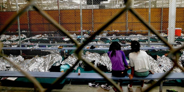 Two young girls watch a World Cup soccer match on a television from their holding area where hundreds of mostly Central American immigrant children are held. Photo / AP