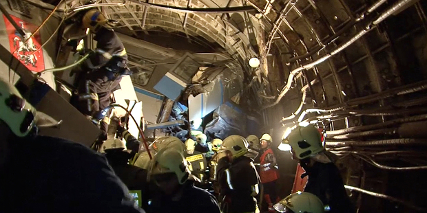 Frame grab from a video showing rescue teams working inside the tunnel where several cars of the wrecked train look almost coiled. Photo / AP