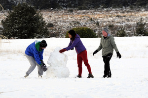 Tourists make the most of the snow on the lawn of the Chateau Tongariro, National Park. Photo / Ross Setford