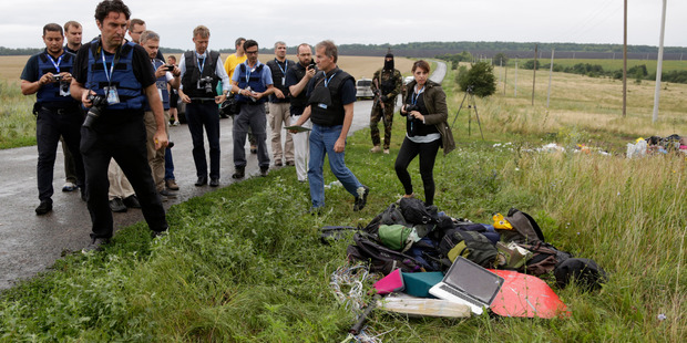 Representatives from the OSCE (Organization for Security and Co-operation in Europe) delegation inspect passengers' personal luggage collected at the site of MH17. Photo / AP