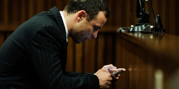 Oscar Pistorius, seen here checking his phone in court, has posted a series of strange tweets. Photo / AP