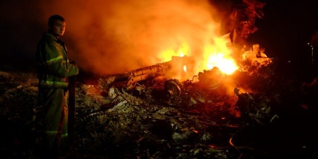 A firefighter stands as flames burst amongst the wreckage of the Malaysia Airlines plane. Photo / AP