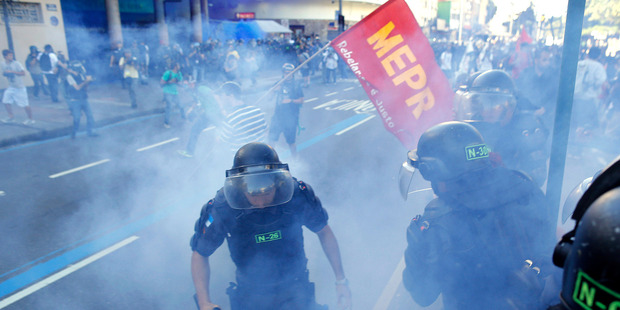 Police set off a smoke grenade during clashes with Anti-World Cup protesters in Rio. Photo / AP