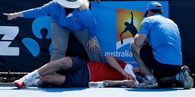 Frank Dancevic of Canada lies on the court after collapsing during his first round match against Benoit Paire of France as temperatures topped at 43 C (108 F). Photo / AP