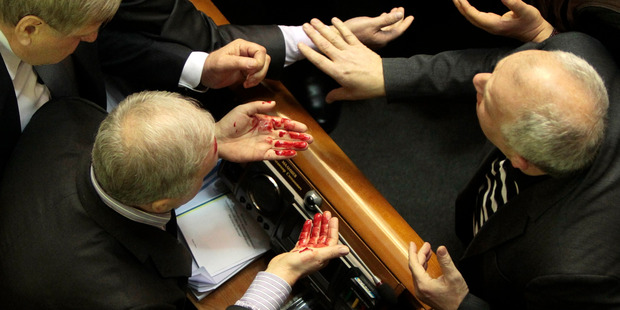 Ukrainian pro-government lawmaker Volodymyr Malyshev, left, wipes blood from his face after a scuffle in the Ukrainian parliament in Kiev, Ukraine. Photo / AP