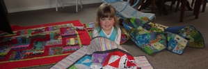 Maddison McQuade, 3, of Napier, with a quilt made by children at this year's Wine Country Quilts Exhibition held near Waipukurau.