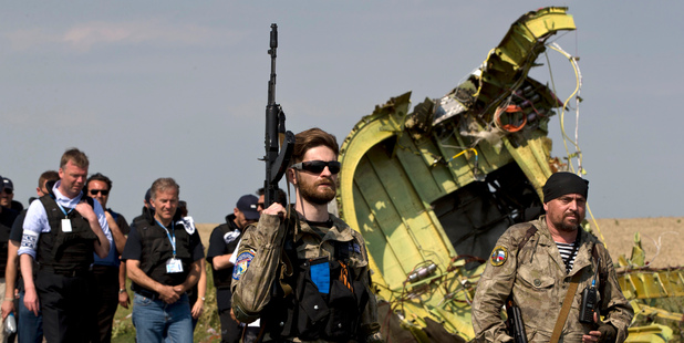 Pro-Russian rebels, right, followed by members of the OSCE mission, walk by the plane wreckage. Photo / AP
