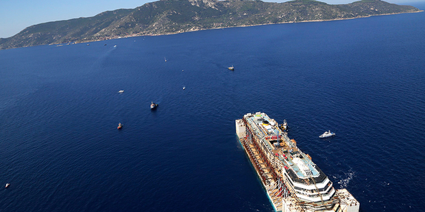 In this aerial picture provided by the Italian Civil Protection Department, the wreck of the Costa Concordia is towed by two tugboats on its final voyage. Photo / AP
