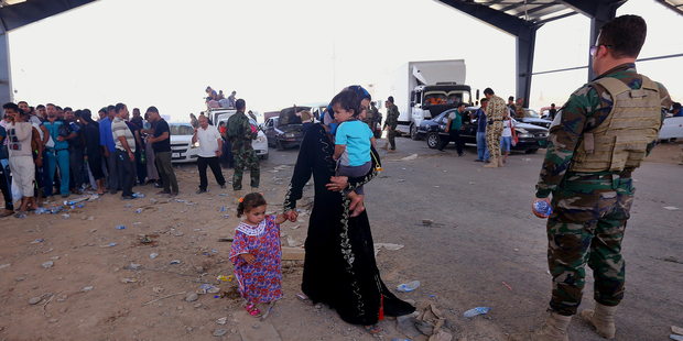 A Kurdish policeman stands guard while refugees fleeing Mosul head to the self-ruled northern Kurdish region in Irbil, Iraq. Photo / AP