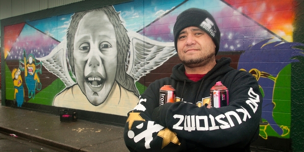 Hastings artist Dallas Halbert and the Camberley shop-wall mural of "the nephew" Uetaha Ransfield-Wanoa, neighbouring the park where Uetaha died in the mower tragedy over eight months ago. Photo / Warren Buckland