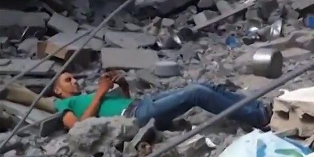 The man on the ground amid rubble after being shot for the first time. Photo / You Tube