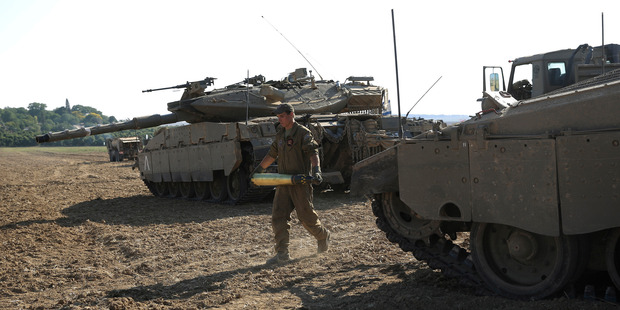 An Israeli soldier carries a tank shell near the border of Israel and the Gaza Strip.