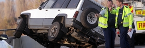 One of the vehicles clipped by a car which failed to stop for slow-moving traffic on the overbridge was left balanced precariously against the railing. Photo / Paul Taylor