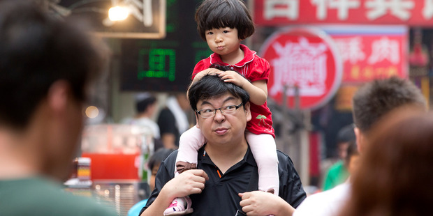 A young girls on her father's shoulders in a market in Xian, China. Photo / Mark Mitchell