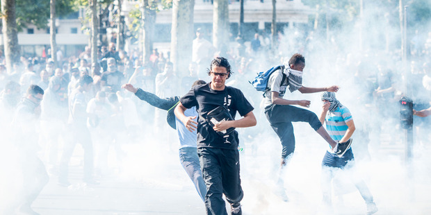 Pro-Palestinian protesters try to escape from a tear gas cloud thrown by riot police during a banned demonstration in support of Gaza at Place de la Republique in Paris, France. Photo / AP