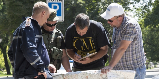 Ukrainian Ministry Emergency officer, left, Donetsk People's Republic fighter, 2nd left, and members of the OSCE mission in Ukraine examine a map of the MH7 crash area. Photo / AP