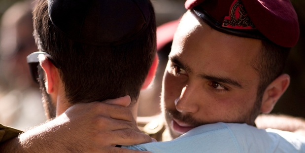 An Israeli officer comforting a friend at a funeral in Meitar, Israel. Photo / AP