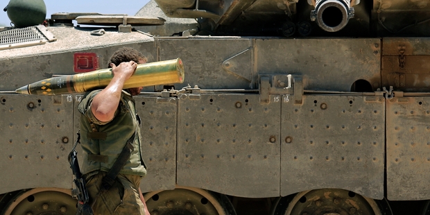 An Israeli soldier carries a tank shell near Gaza during shelling last week. Photo / AP