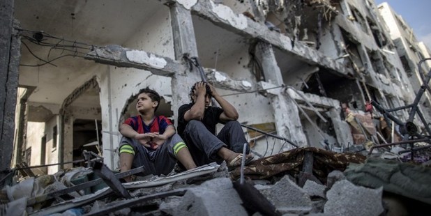 Palestinian brothers sit on the rubble of their house in front of an apartment block in part of the northern Beit Hanun district of the Gaza Strip. Photo / AFP