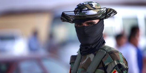 An Iraqi Kurdish security guard waits to check the ID cards of Iraqi families fleeing violence in the northern Nineveh province as they gather at a Kurdish checkpoint. Photo / AFP