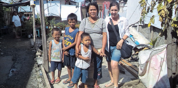 Julie McGowan with one of the families affected by Typhoon Haiyan in the Philippines.and their new house. Photo / Pete McGowan