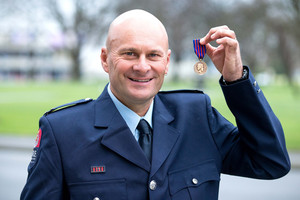 Christchurch fireman Terry Gyde holds his New Zealand Bravery Award at the Transitional Cathedral. Photo / Martin Hunter