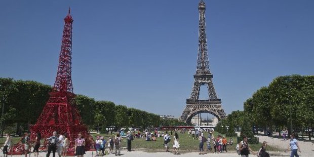People stroll in front of a replica of the Eiffel Tower, build out of bistro chairs. Photo / AP