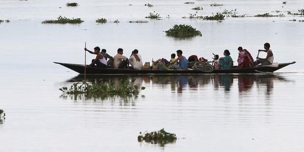 Villagers row towards higher ground in Assam state, India. Photo / AP