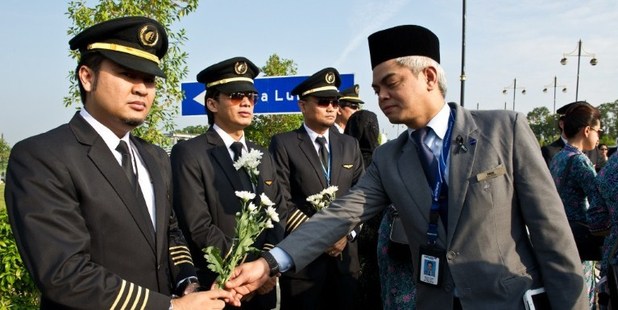 A man gives white flowers to a Malaysia Airlines pilot before the arrival of the Malaysian remains who perished aboard flight MH17. Photo / AFP