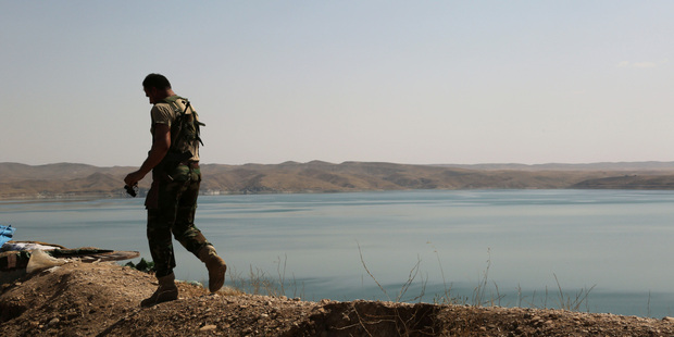 A Kurdish peshmerga fighter patrols near the Mosul Dam at the town of Chamibarakat outside Mosul, Iraq. Photo / AP