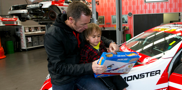 Racing driver Greg Murphy helps Wiremu Le Comte open present in his East Tamaki workshop. Photo / Jason Oxenham
