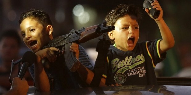Children hold up guns (one with an empty magazine) from a car as Palestinians gather in the streets to celebrate a ceasefire which ends 50 days of conflict. Photo / AFP