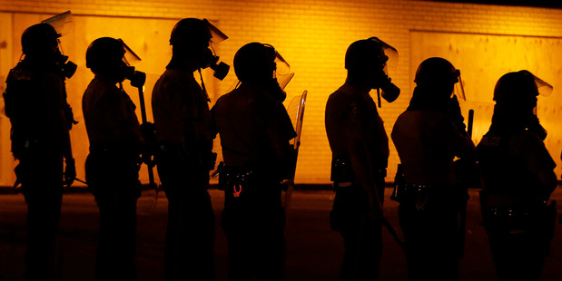 Police wait to advance after tear gas was used to disperse a crowd during a protest for Michael Brown. Photo / AP