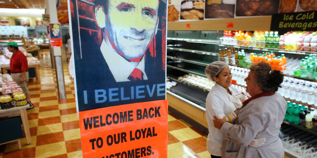 Market Basket employees embrace near a likeness of Arthur T. Demoulas, at a Market Basket supermarket following news the Demoulas has won a bid to buy the chain. Photo / AP