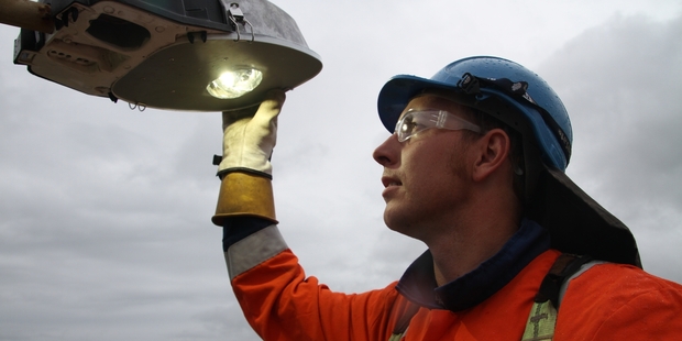 Northpower trainee lineman Derryn Cooper installs smart street lights at Baylys Beach. Photo / Supplied