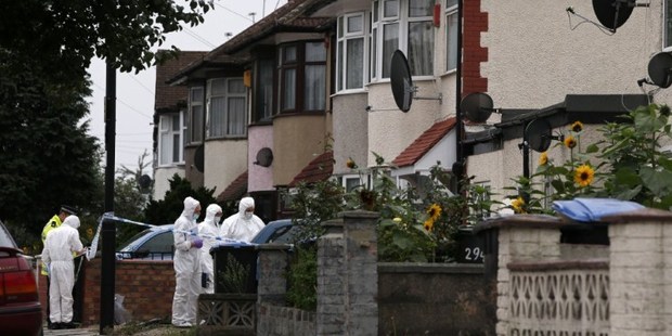 Police forensics personnel examine the scene on a street in Edmonton, north London, after a woman was found dead following a beheading. Photo / AFP