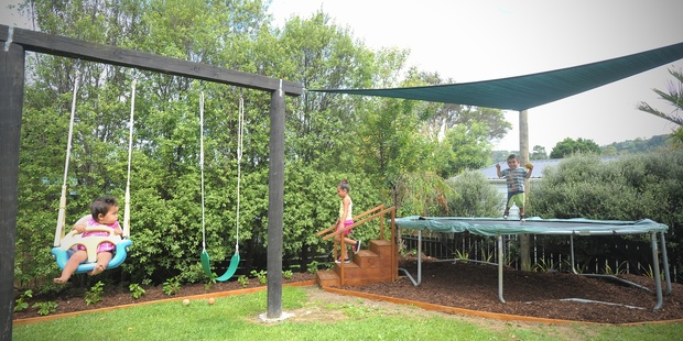 DIY. Play area with swings, shade sail, and steps up to a trampoline. Photo / Jason Dorday