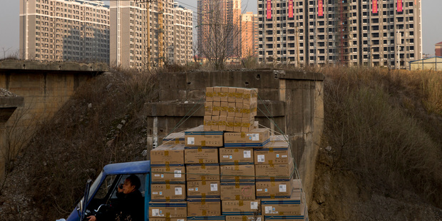 A man in a cart loaded with goods near under-construction residential buildings in Changsha, in the Hunan province. Chinese GDP growth for the last quarter was 7.7 per cent. Photo / AP