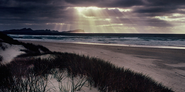 Light rays filter through the clouds at dusk along Mason Bay, Stewart Island. Photo / Hawkes Bay Today